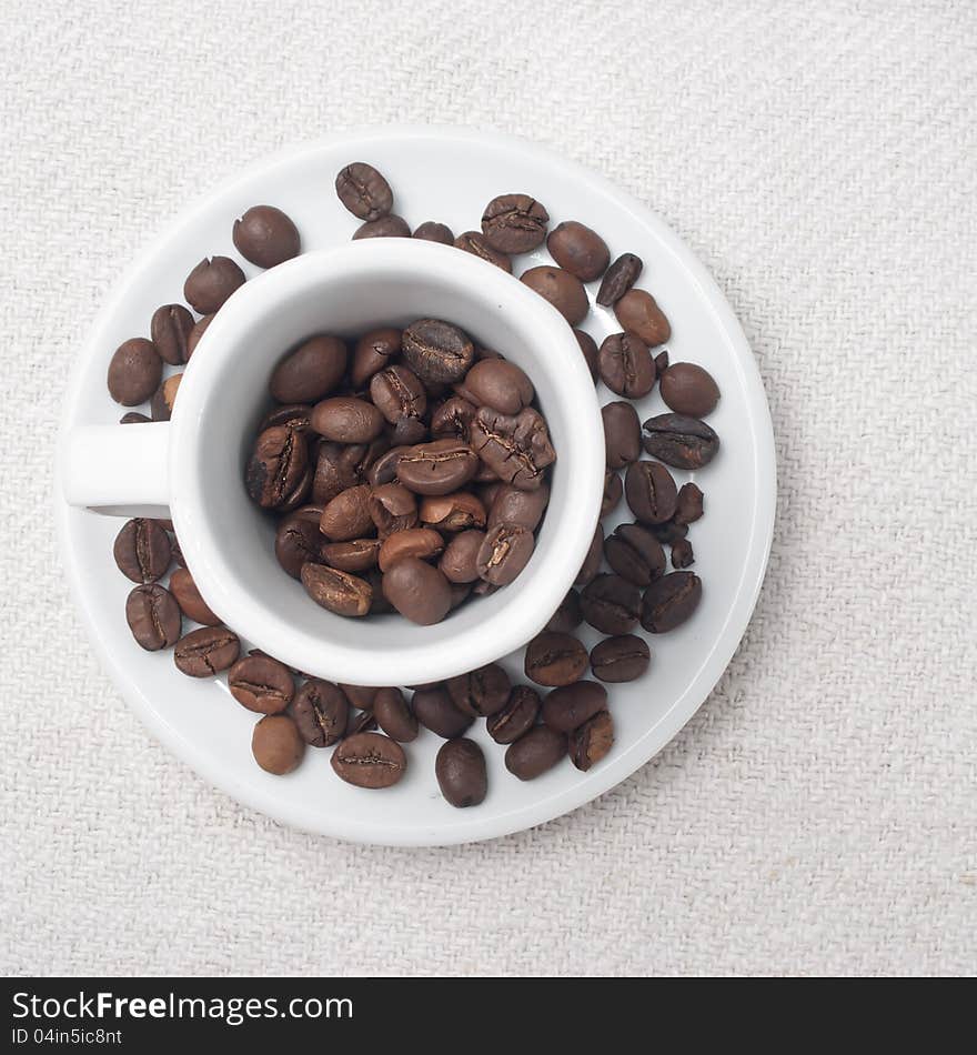 Coffee beans in a cup on white fabric