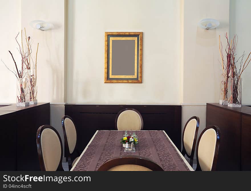 Just one corner of a restaurant, empty table and chairs with empty frame on the wall. Just one corner of a restaurant, empty table and chairs with empty frame on the wall.