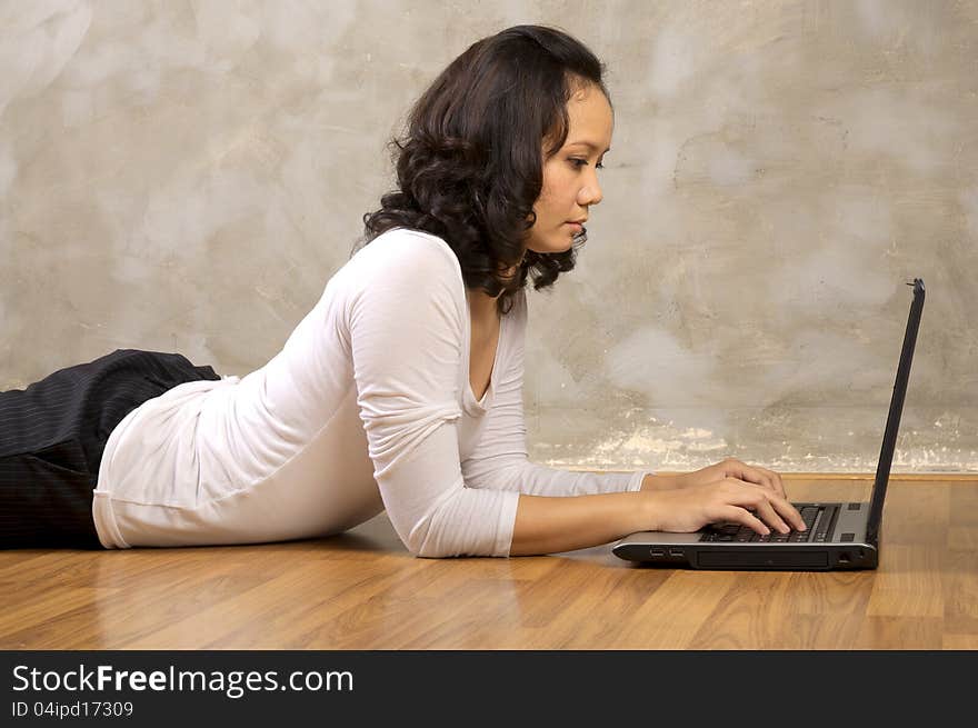 Woman lying on the wooden floor using laptop notebook. Woman lying on the wooden floor using laptop notebook