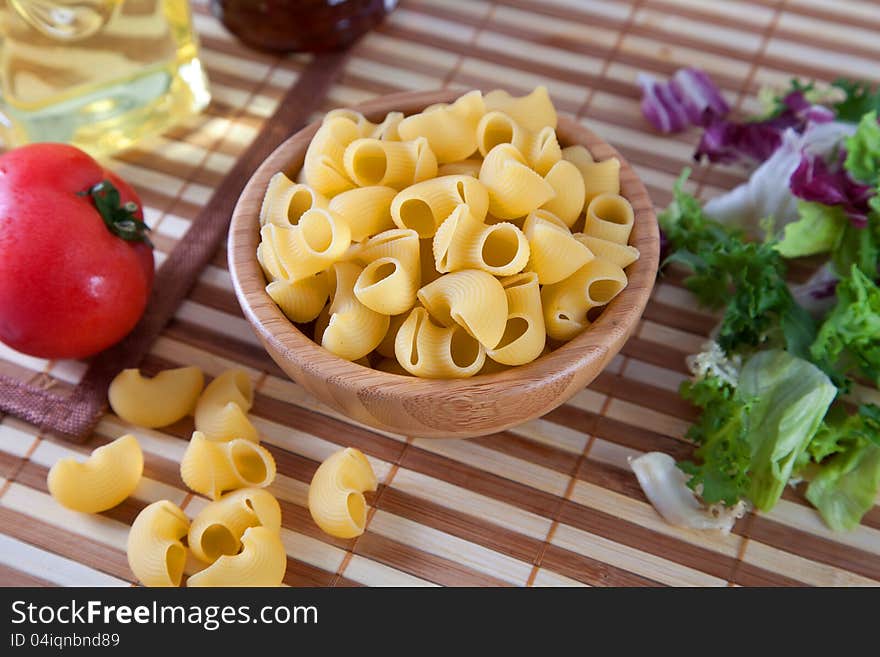 Uncooking pasta in bamboo bowl on table.