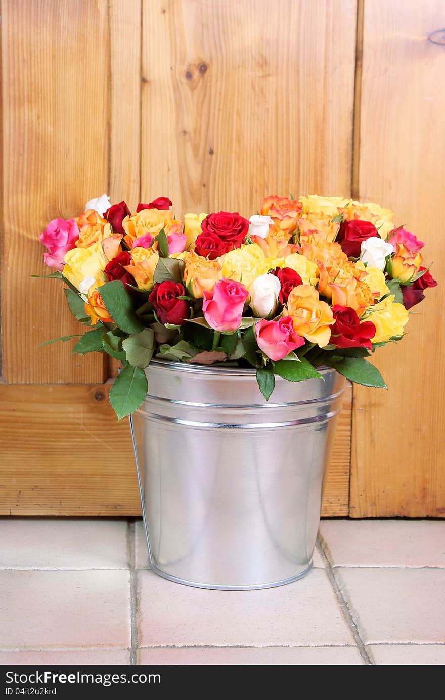 Bunch of roses in tinny bucket on a wooden background. Bunch of roses in tinny bucket on a wooden background