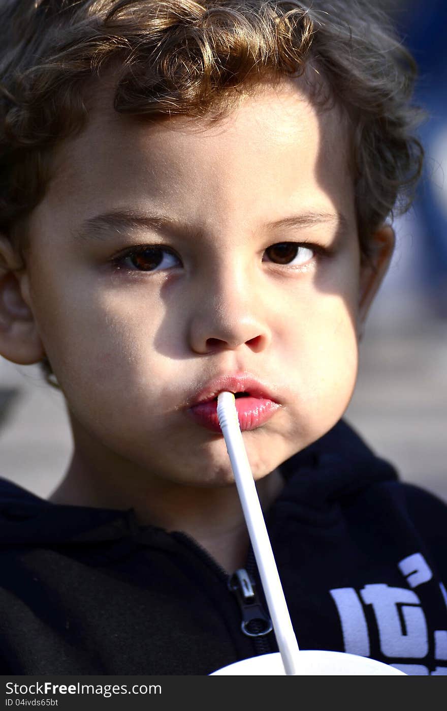 A kid drinking a milkshake, viewing to you.