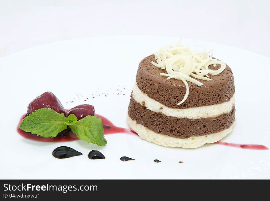 A piece of cream cake decorated with chocolate and mint. A piece of cream cake decorated with chocolate and mint