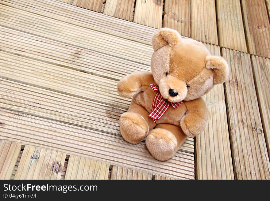 Photo of soft brown teddy bear sitting on newly laid decking. Photo of soft brown teddy bear sitting on newly laid decking.