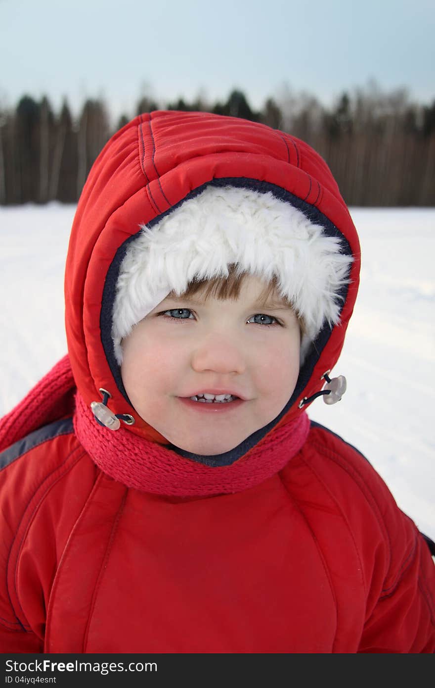 Happy little girl smiles near forest at winter