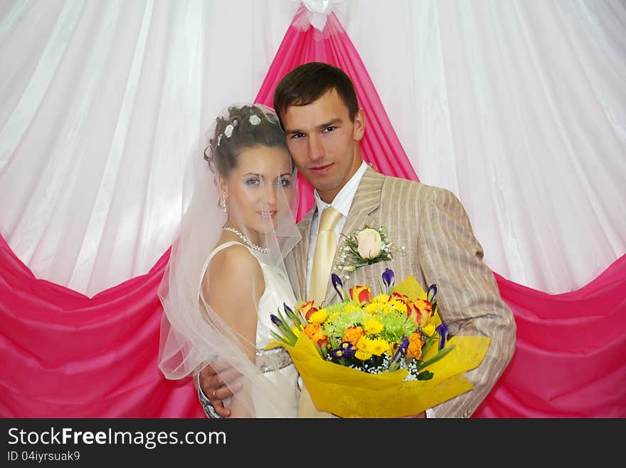 Happy groom with flowers hugs his bride