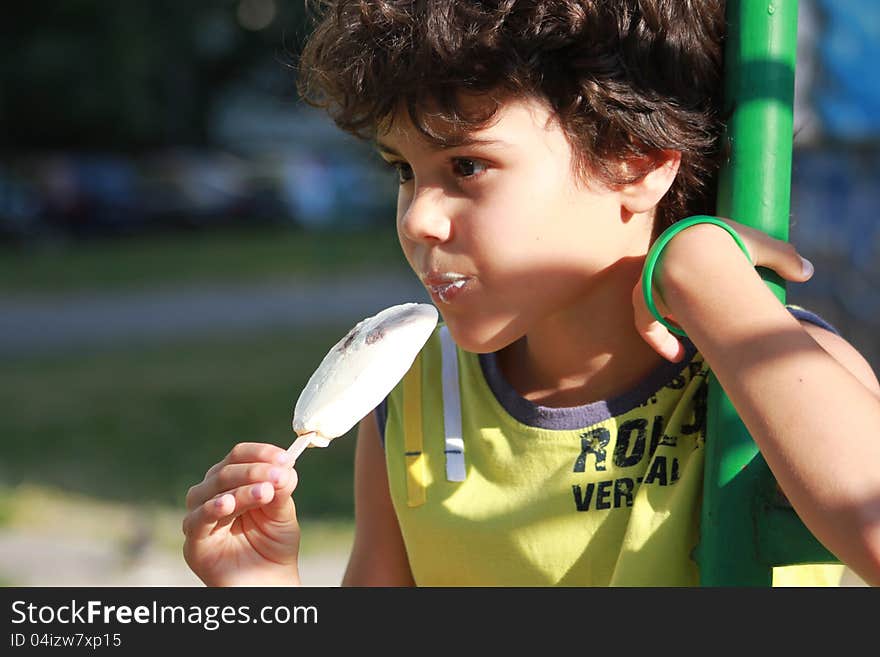 Cute boy eating an ice cream outside