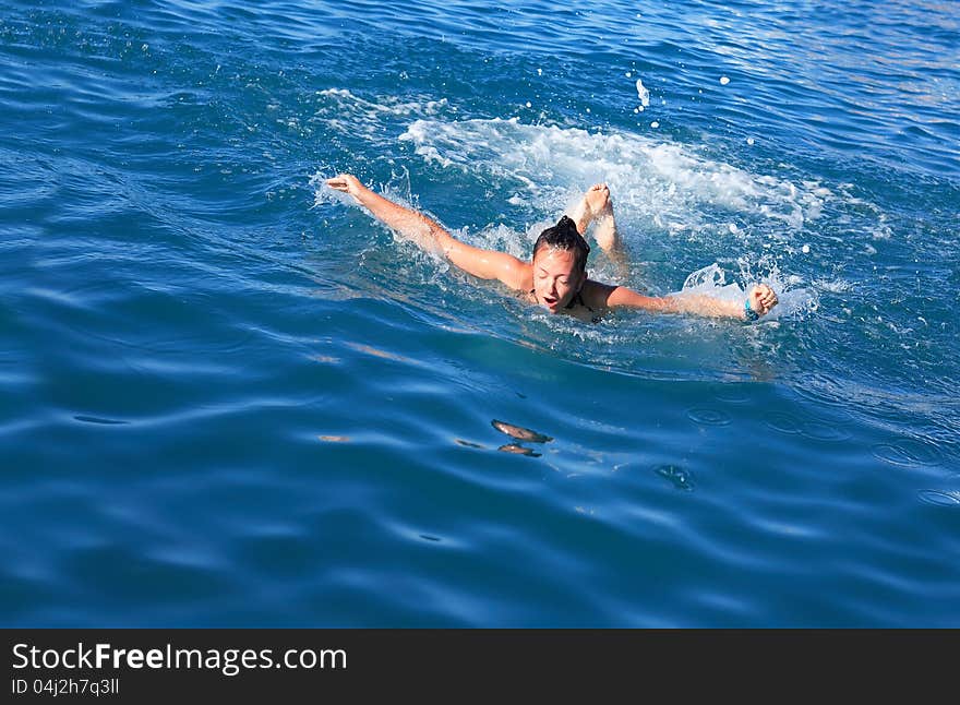 Beauty teenage girl swimming the butterfly stroke in a sea. Beauty teenage girl swimming the butterfly stroke in a sea