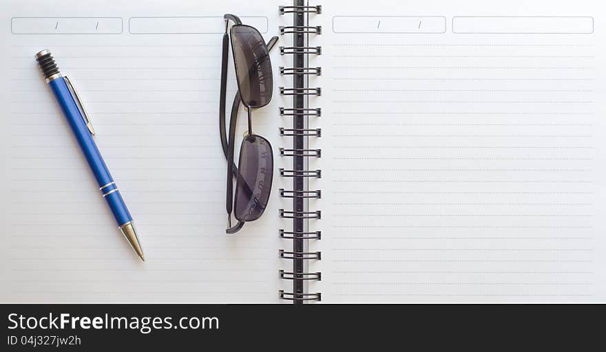 Notebook with pencil and sunglasses