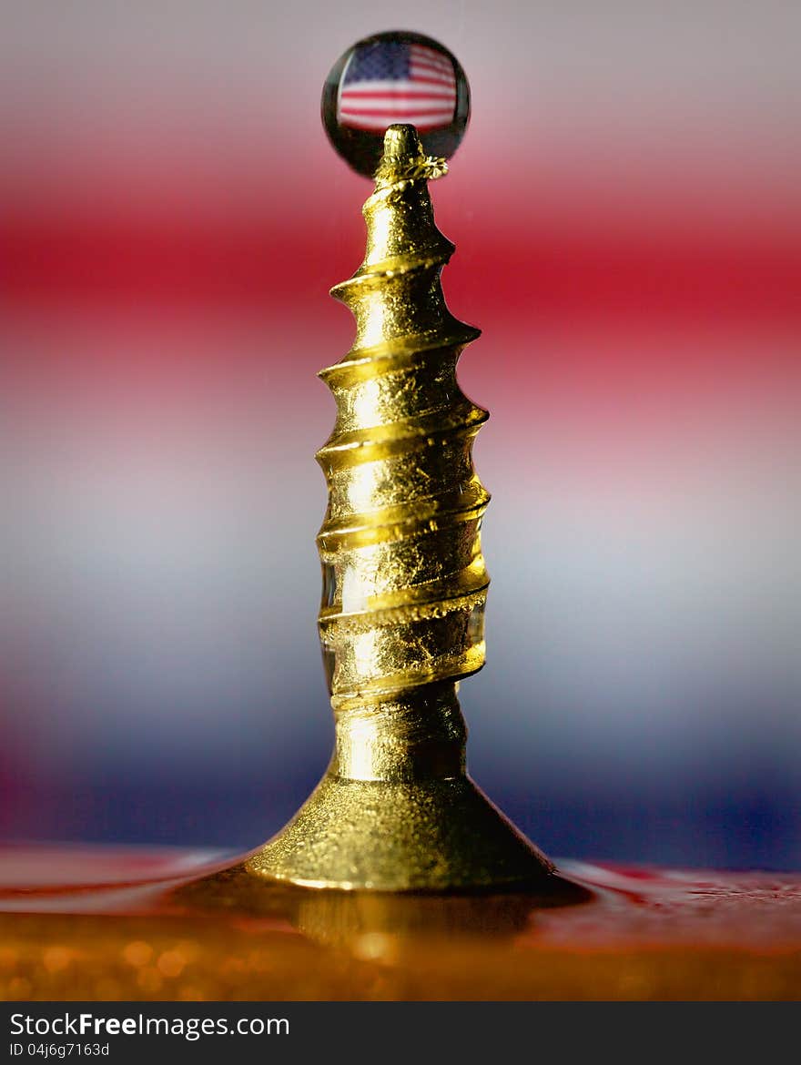 A waterdrop caught as it hits a screw. The drop has an image of the USA flag refracted through it. A waterdrop caught as it hits a screw. The drop has an image of the USA flag refracted through it