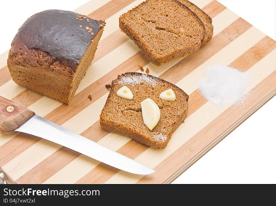 Sliced bread with the chunk and knife on a kitchen board, with a scary face made of bread and garlic. Sliced bread with the chunk and knife on a kitchen board, with a scary face made of bread and garlic.