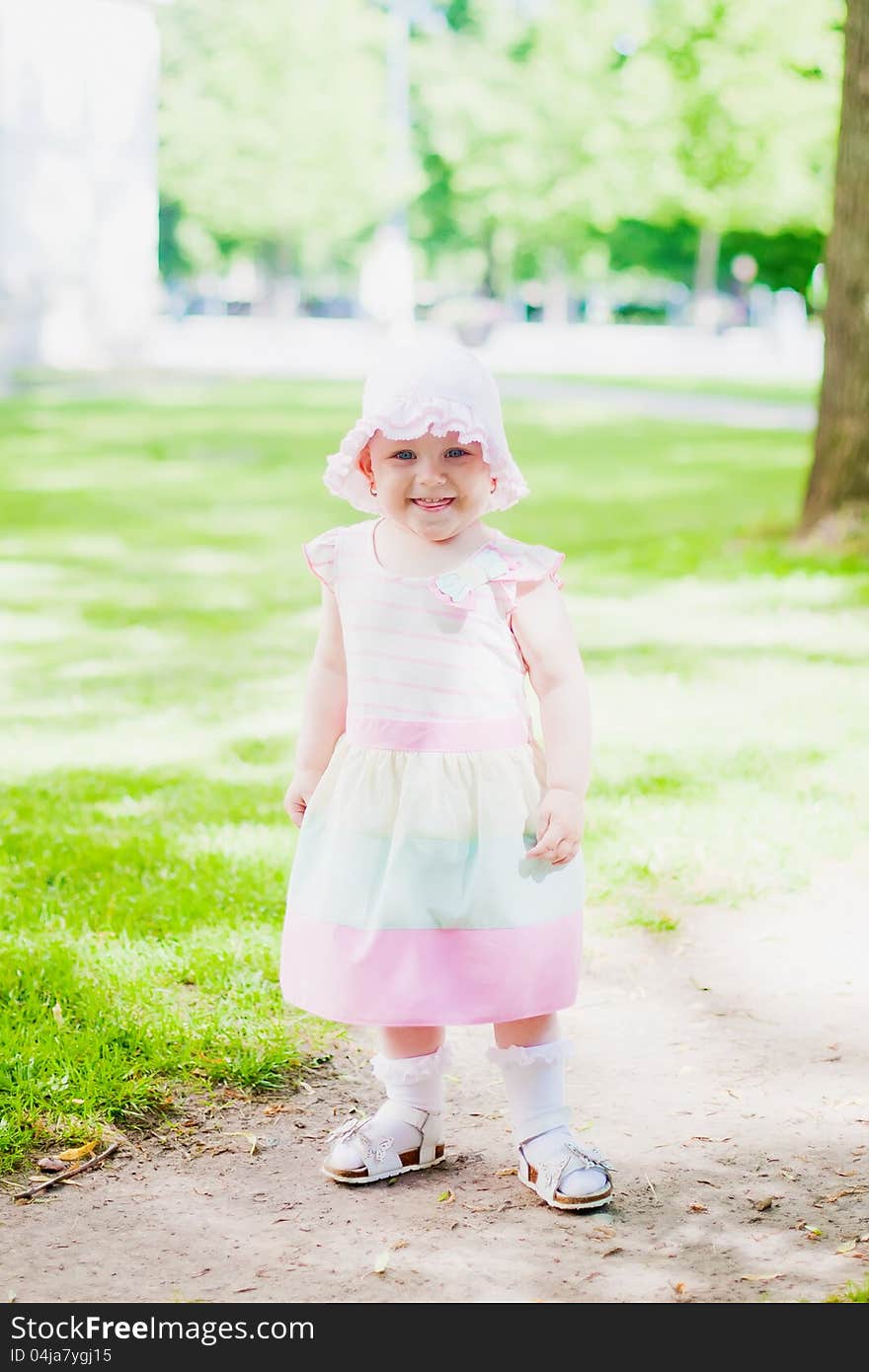 Toddler girl in pink dress and hat smiling and showing her tongue. Toddler girl in pink dress and hat smiling and showing her tongue