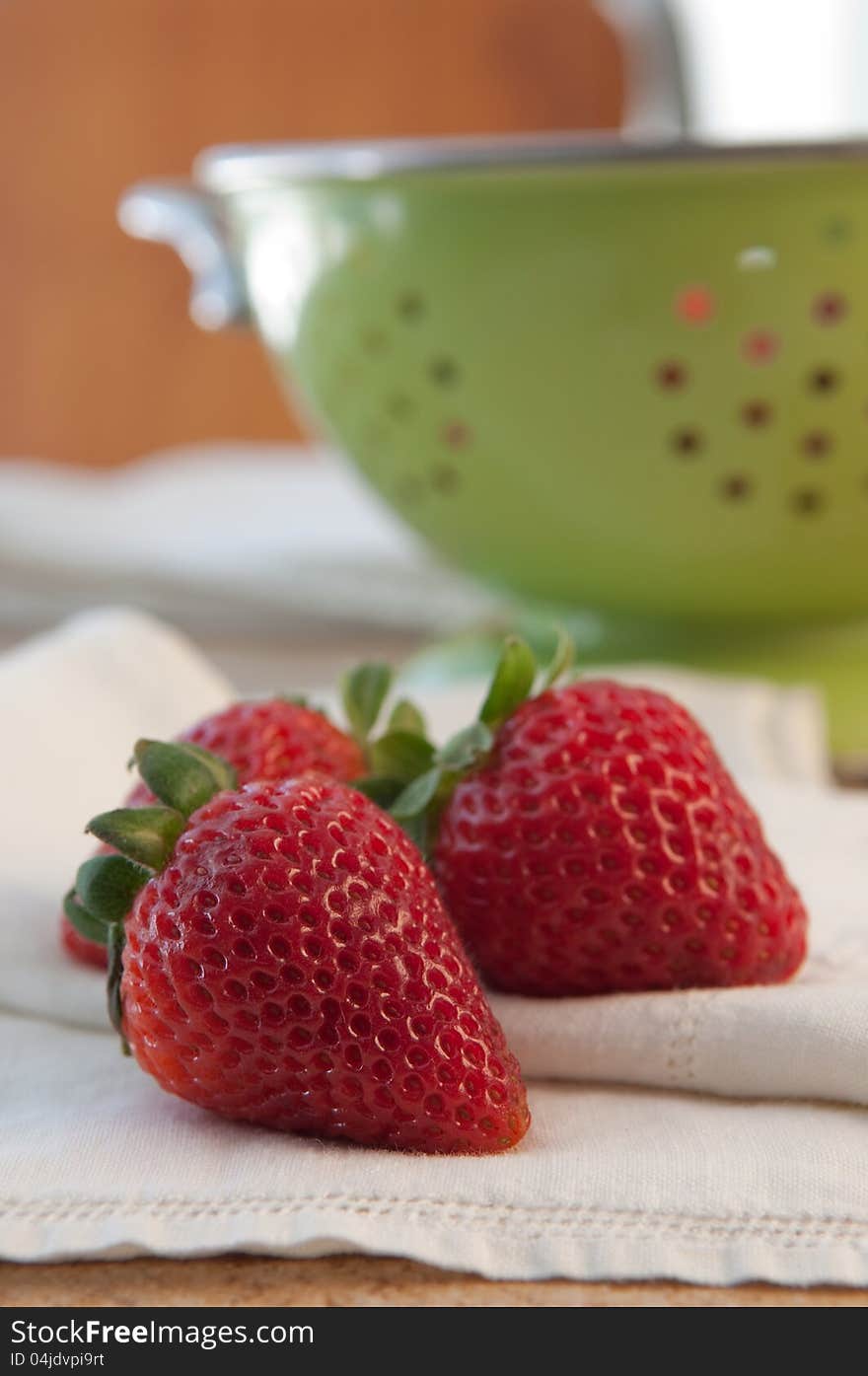 Three fresh delicious ripe strawberries with colander on white cloth. Three fresh delicious ripe strawberries with colander on white cloth