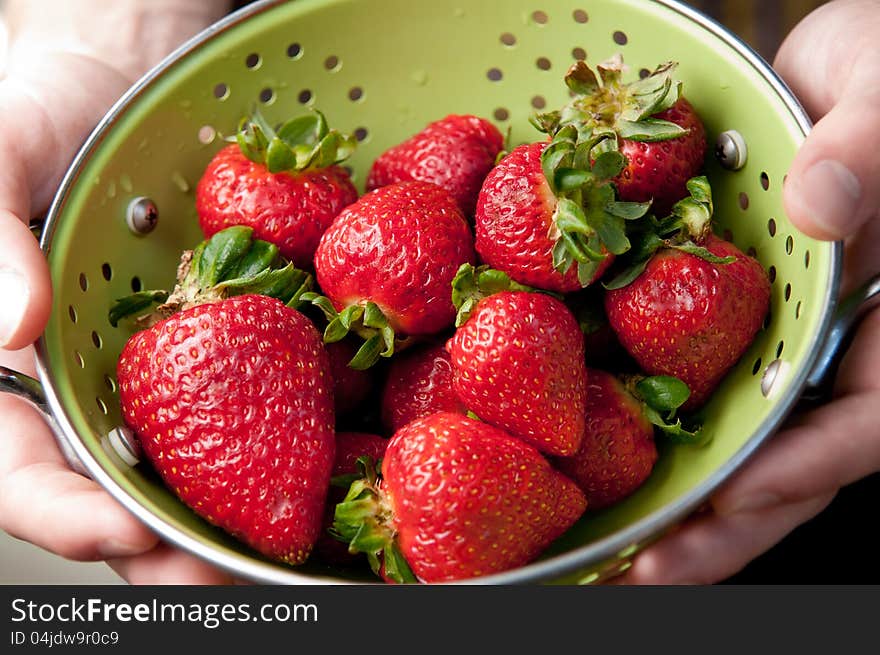 Hands Holding Colander Of Strawberries