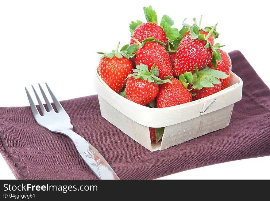 The composition of strawberries in a basket and a fork. On a white background.