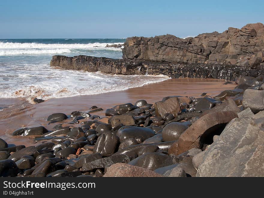 Wet boulders gleaming in the sun after the waves have washed over them on a beach at Ballito, KwaZulu-Natal North Coast, South Africa. Wet boulders gleaming in the sun after the waves have washed over them on a beach at Ballito, KwaZulu-Natal North Coast, South Africa