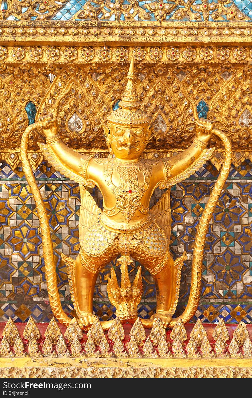 The statue of Garuda battling naga serpent on the wall of temple in Thailand. The statue of Garuda battling naga serpent on the wall of temple in Thailand