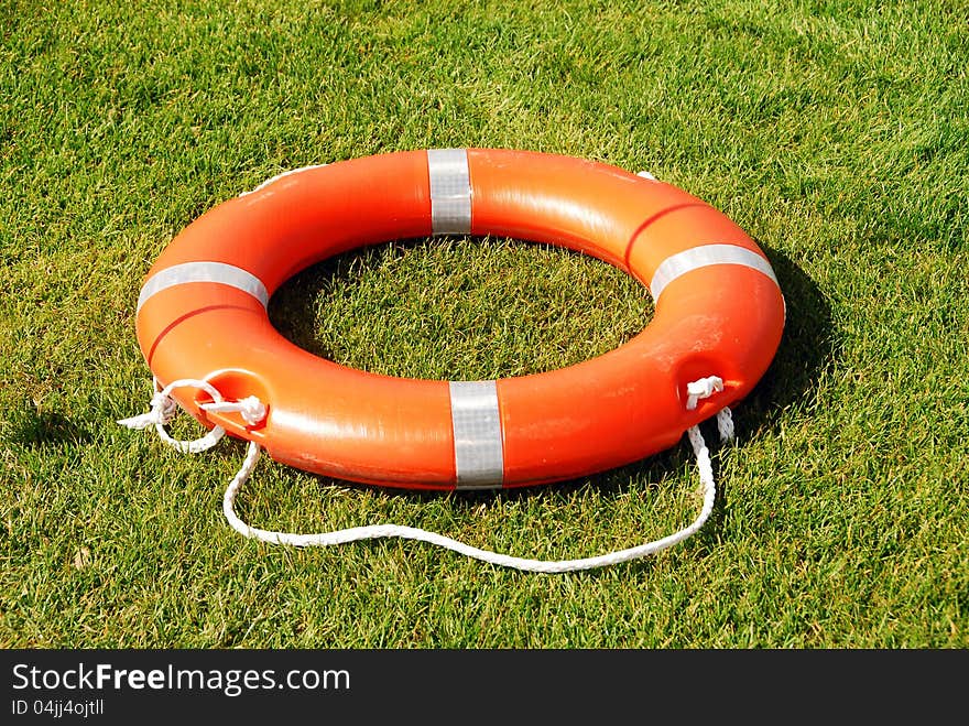 An orange flotation device in grass