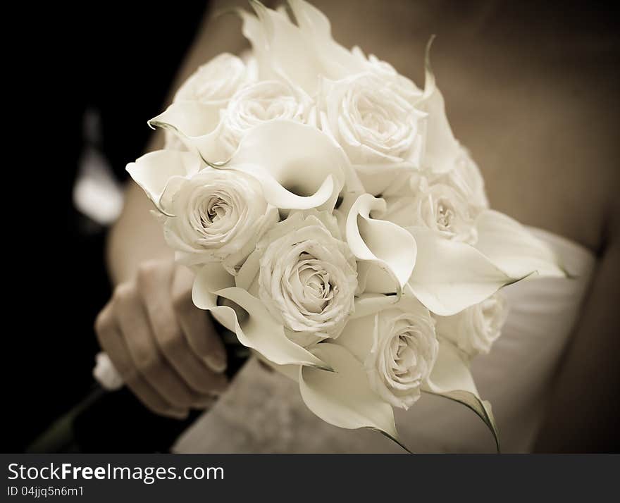 Bride holding white wedding bouquet - sepia