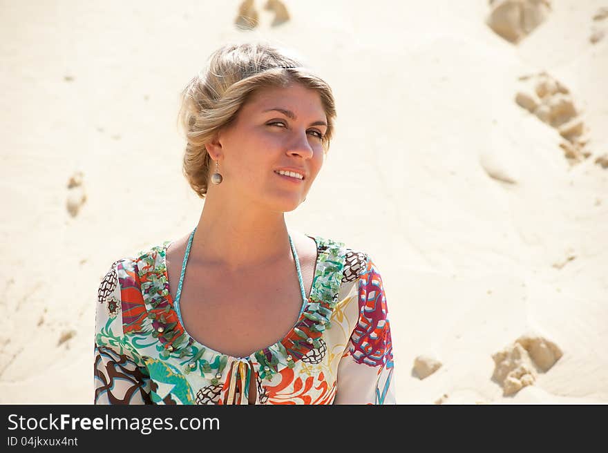 Portrait of a blonde in a sarafan on the background the sand