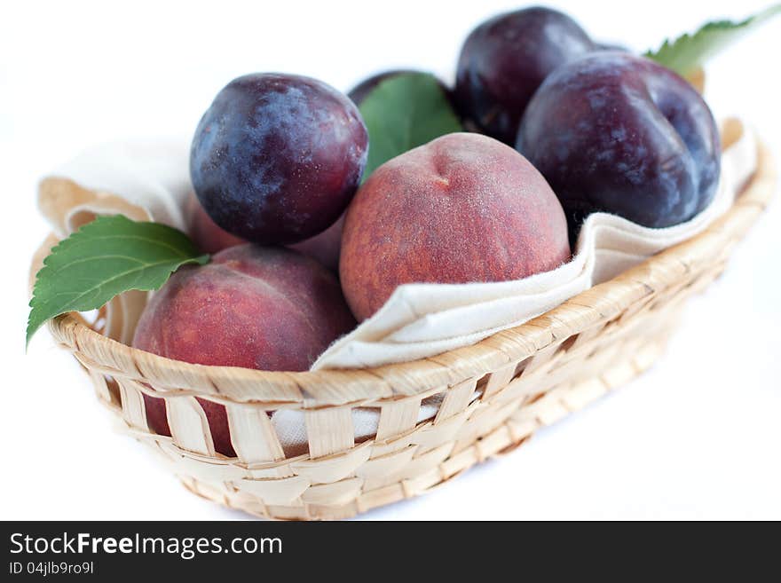 Ripe peaches and plums in the basket, closeup