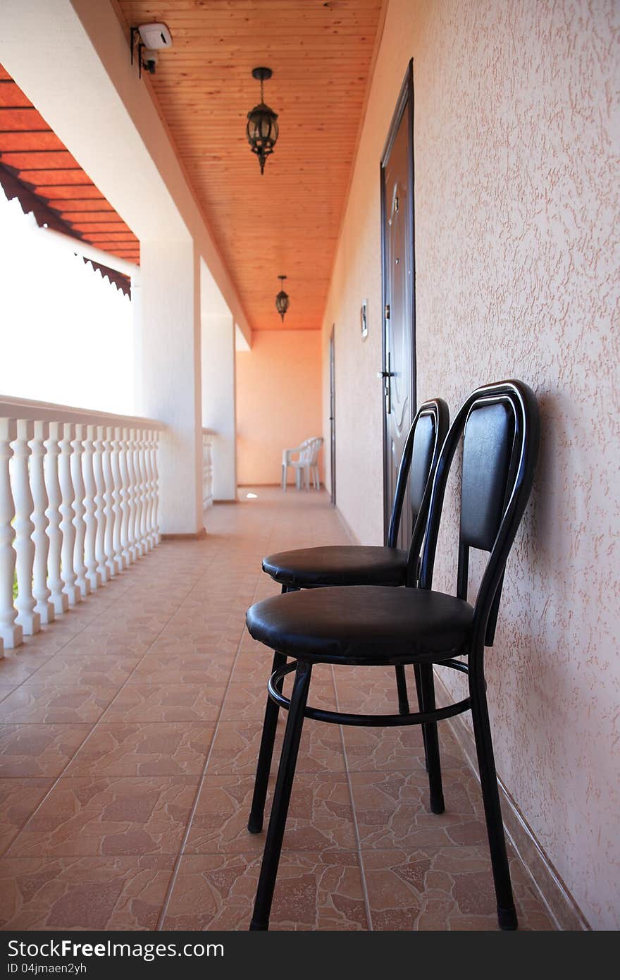 Pair of chairs standing on long terrace with white railing. Pair of chairs standing on long terrace with white railing