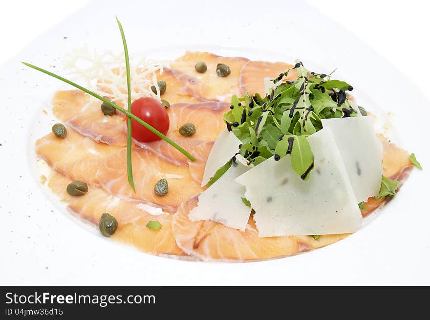 Slices of salmon with herbs and cheese on a white plate