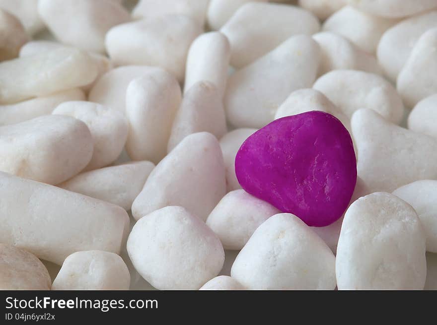 One purple stone in the group of white stone. One purple stone in the group of white stone