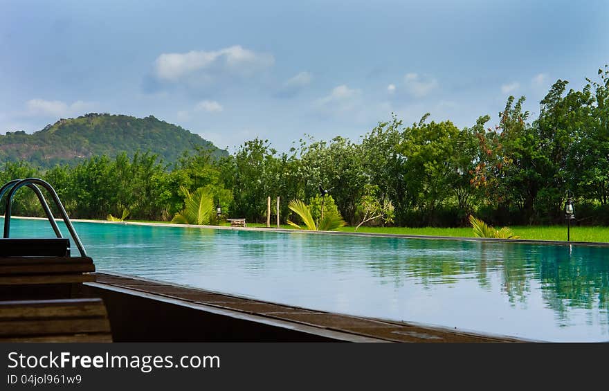 Beautiful refreshing calm blue pool with reflections backed by tropical vegetation. Beautiful refreshing calm blue pool with reflections backed by tropical vegetation