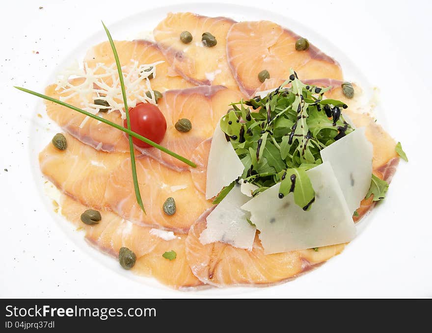 Slices of salmon with herbs and cheese on a white plate