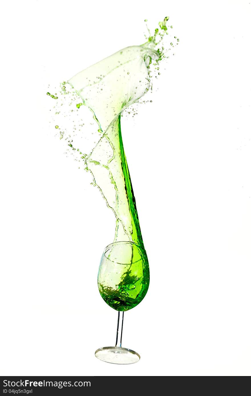 A wine glass spilling green liquid upwards. A wine glass spilling green liquid upwards