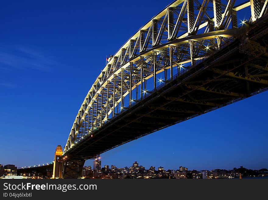 Sydney Harbour Bridge taken at dusk, where the sky is rich blue and where the north shore is visible