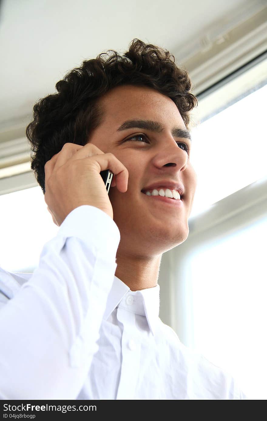 Image of a happy businessman making a phone call in his office