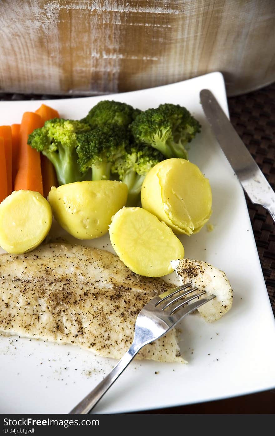 Baked fish on fork with veagetables on white plate. Baked fish on fork with veagetables on white plate