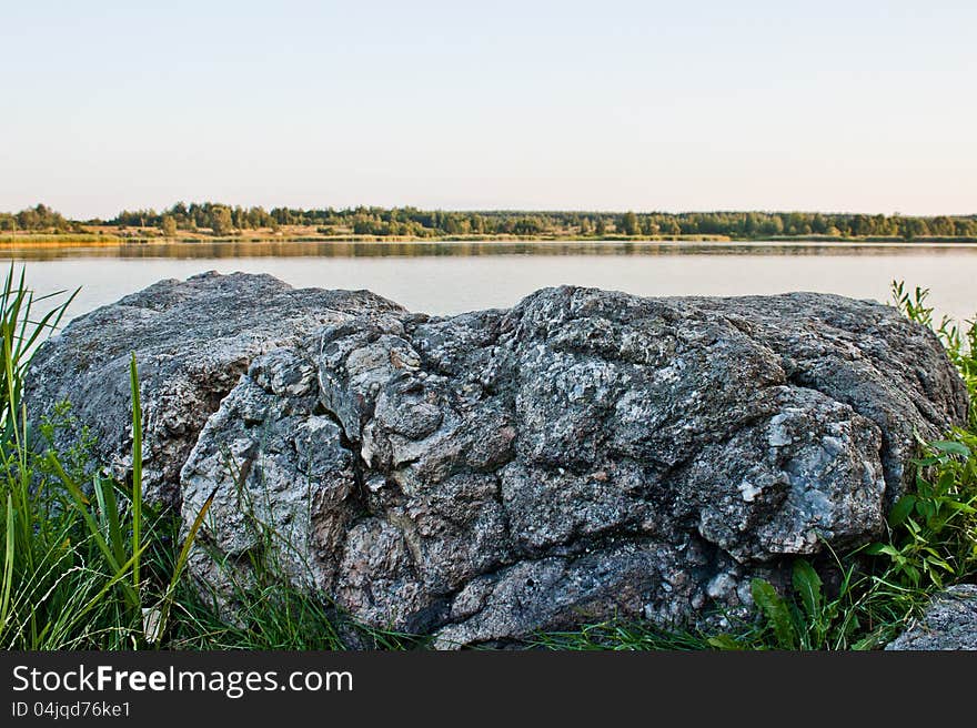 Sky, stone and green trees in nature over lake with reflections