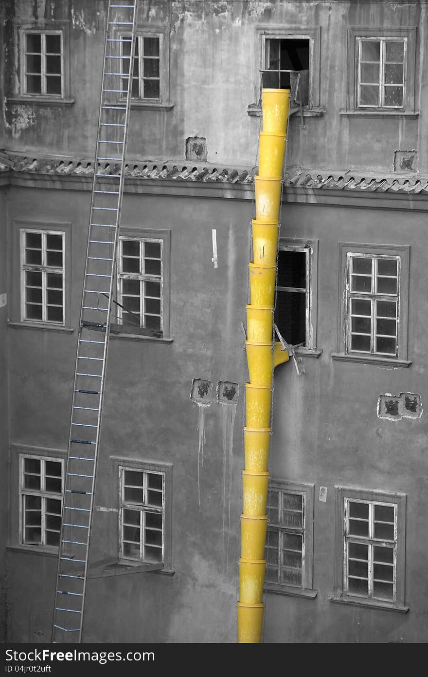 Yellow pipe on the rubble of the house attached to the window, long ladder leaning against the wall of the house. Yellow pipe on the rubble of the house attached to the window, long ladder leaning against the wall of the house