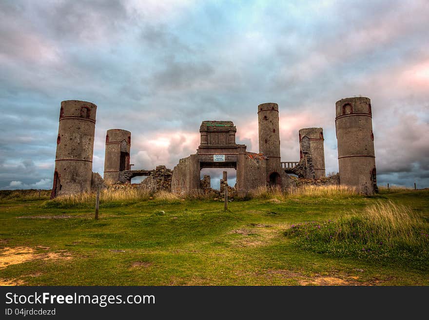 Old stone ruins of a castle or house or mansion in medievel France with a dramatic grey cloudy sky in the background and bright green grass in the foreground. This is a high dynamic range image. Old stone ruins of a castle or house or mansion in medievel France with a dramatic grey cloudy sky in the background and bright green grass in the foreground. This is a high dynamic range image.