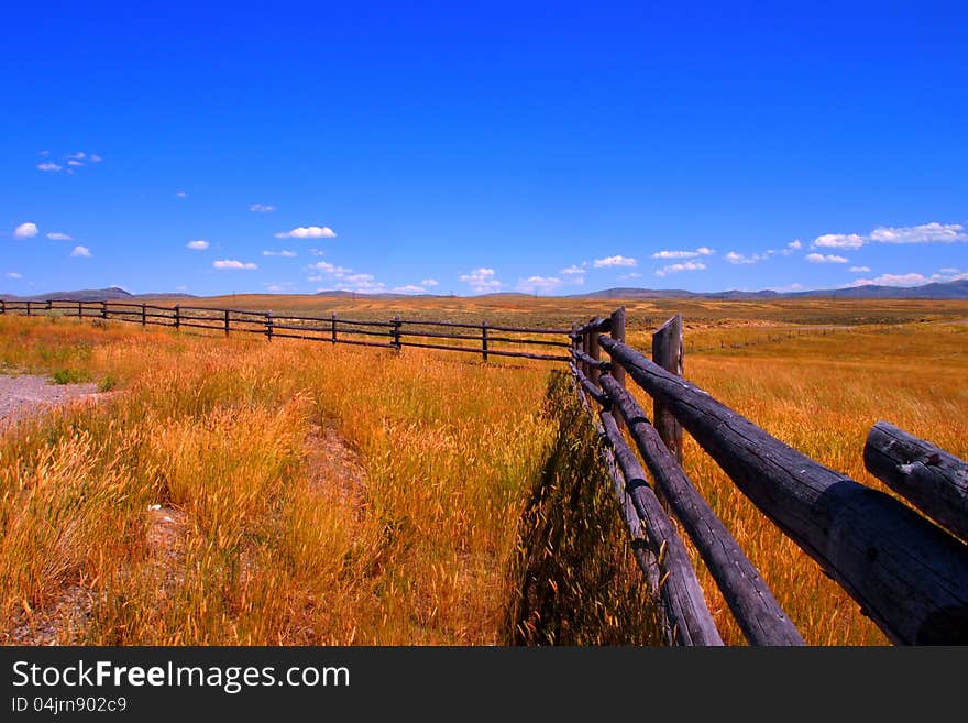 Grass field with wood fence and blue sky