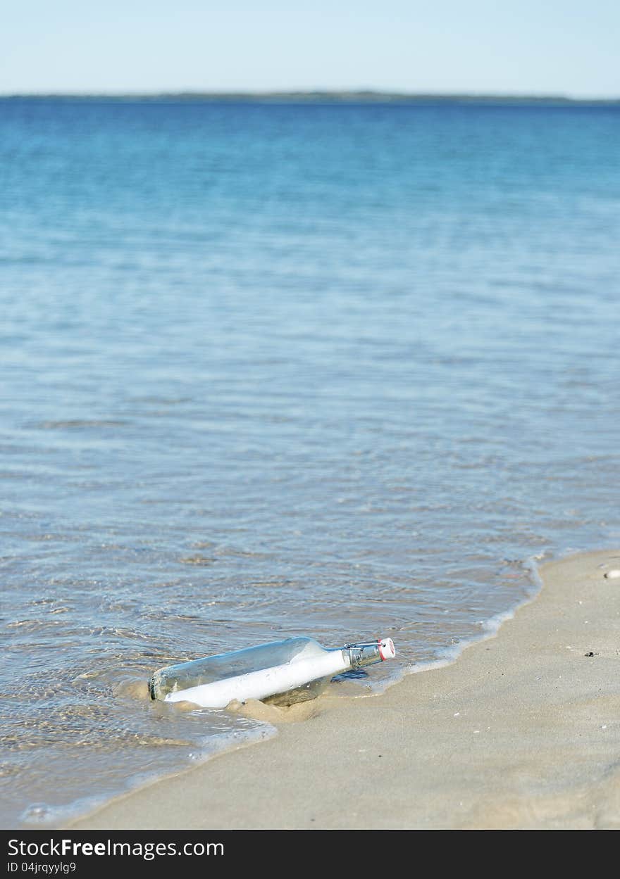 Message in a bottle being washed up on a deserted beach. Copyspace. Message in a bottle being washed up on a deserted beach. Copyspace.