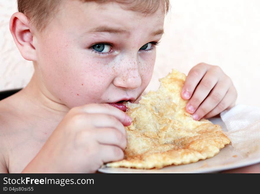 Closeup portrait of little boy eating meat pie named �cheburek�. Closeup portrait of little boy eating meat pie named �cheburek�