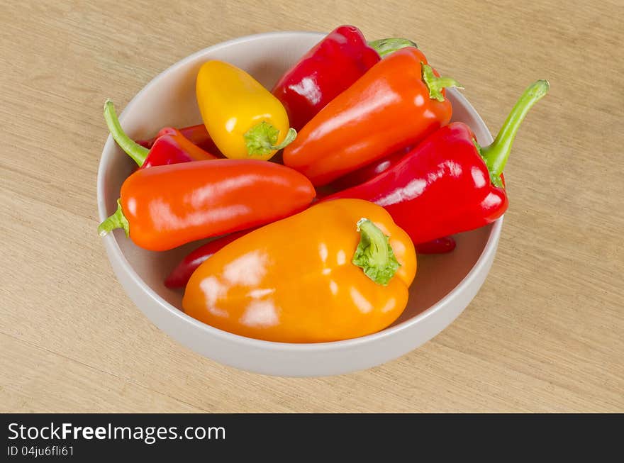 A bowl full of red, orange and yellow sweet peppers. A bowl full of red, orange and yellow sweet peppers.