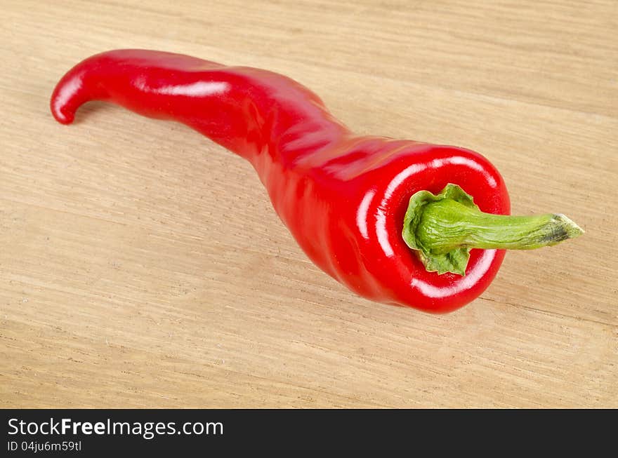 One red hot pepper on an oak surface.