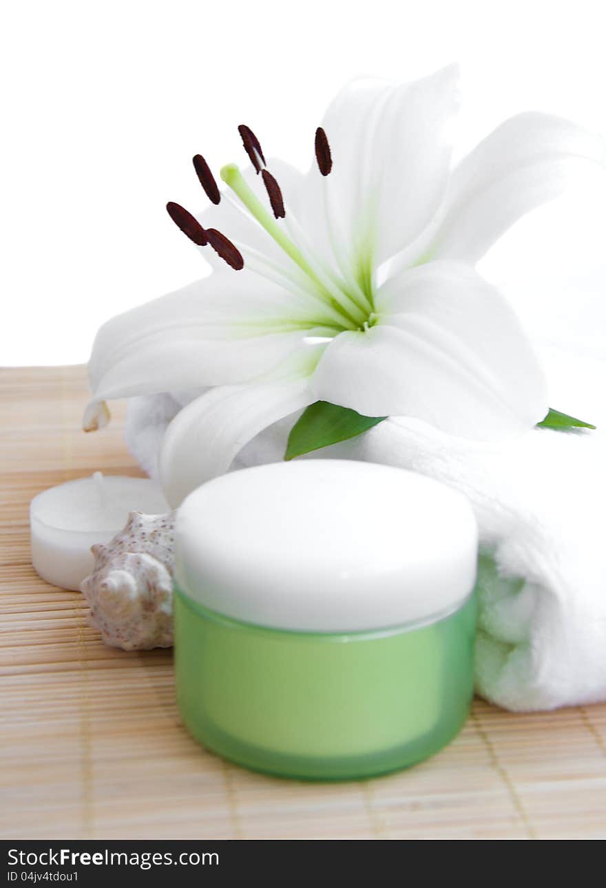 White lily, towel, candle, body cream on white background. White lily, towel, candle, body cream on white background