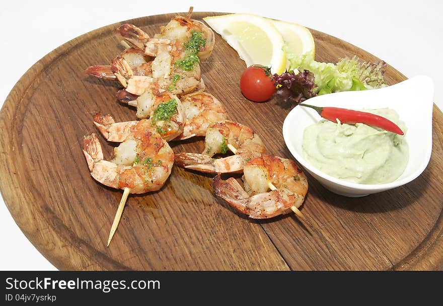 Grilled shrimp with a salad on a wooden plate