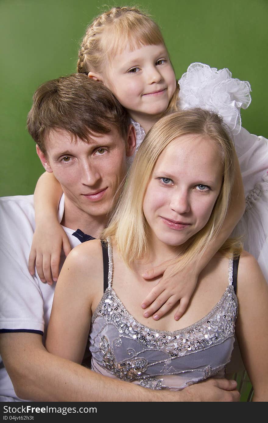 Young European family from three persons - mother, father and daughter. On a green background. Young European family from three persons - mother, father and daughter. On a green background.