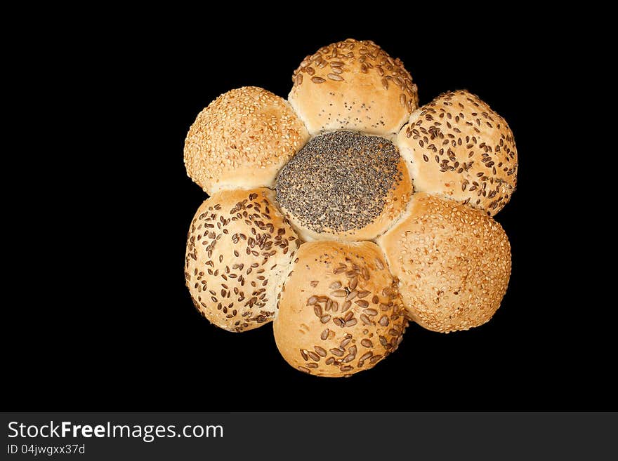 Bread looking lika a flower, full of different seeds. Isolated on black background. Bread looking lika a flower, full of different seeds. Isolated on black background.