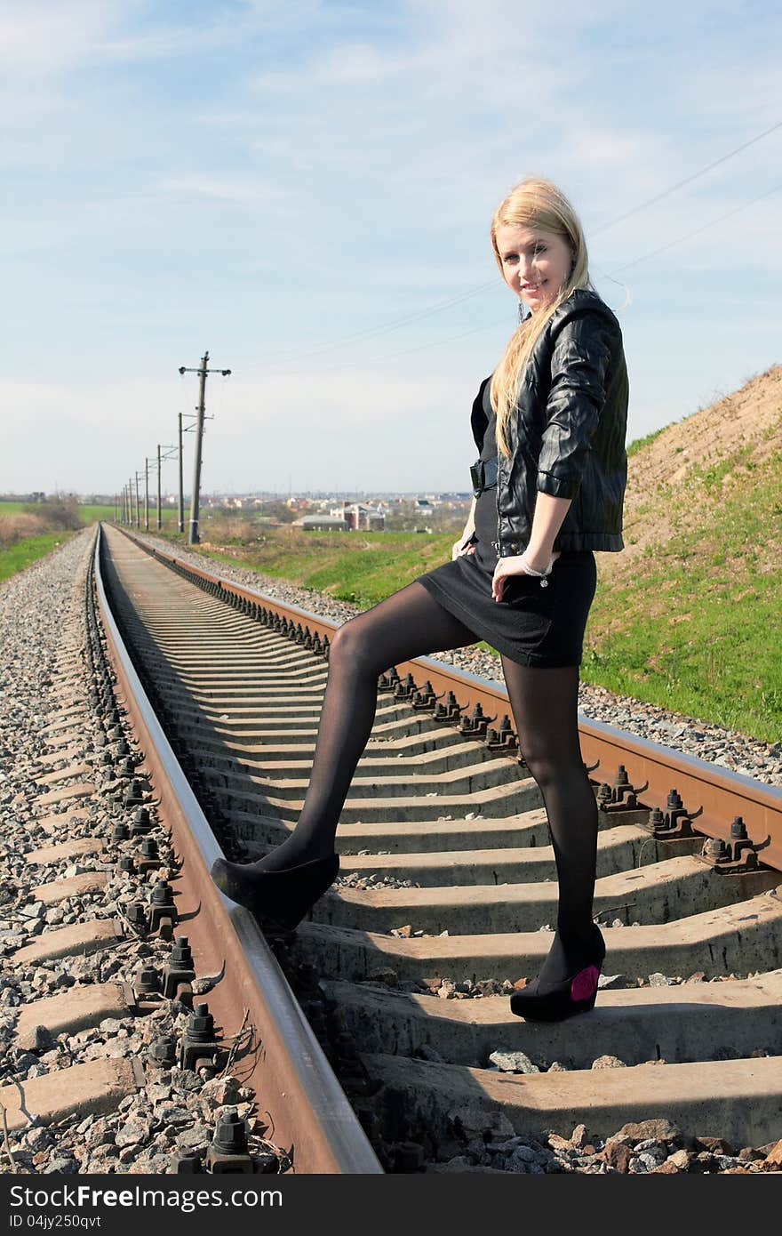 Attractive young girl standing on railroad tracks