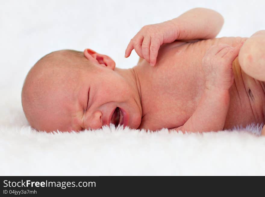 Unhappy crying newborn baby on fluffy blanket. Unhappy crying newborn baby on fluffy blanket