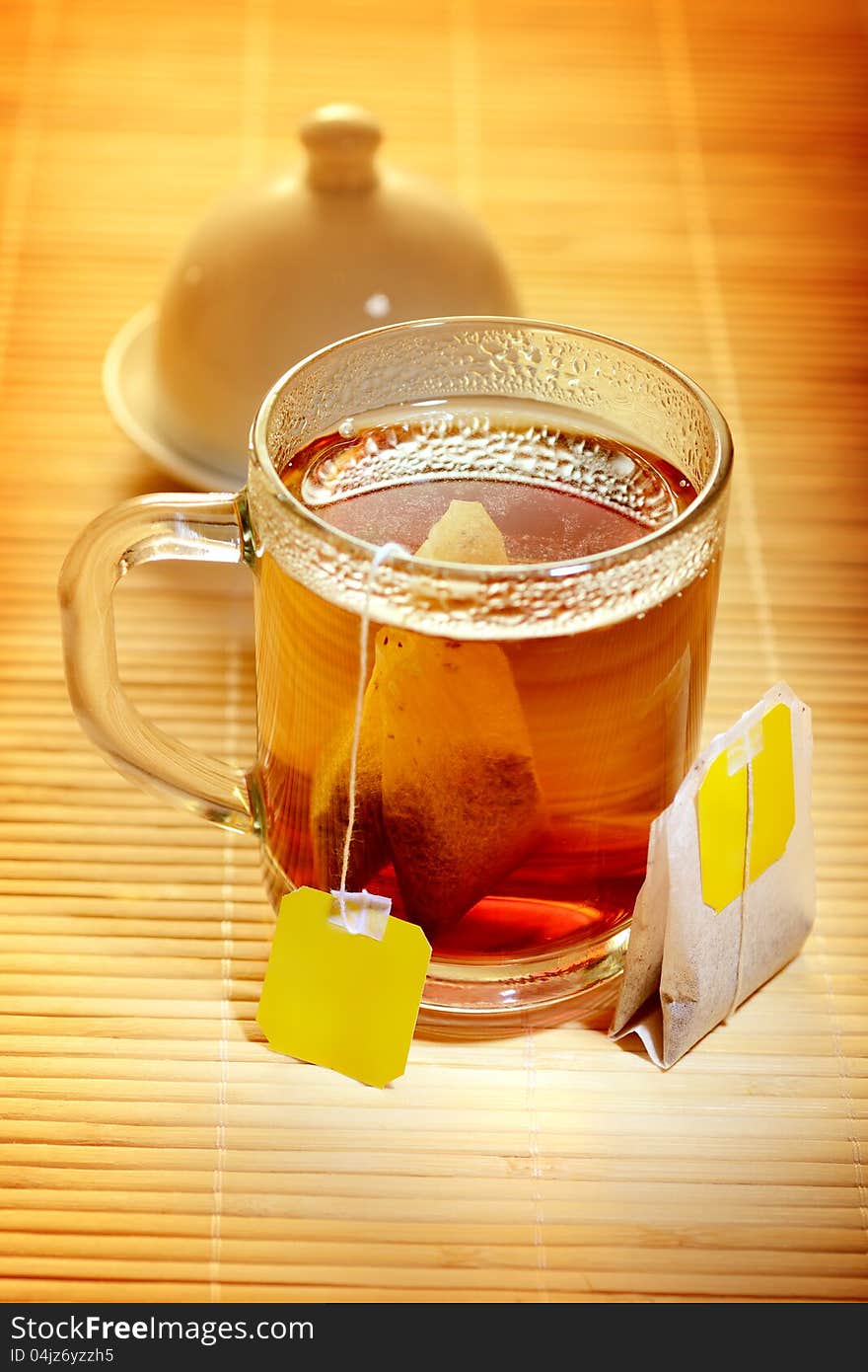 A cup of tea with tea bags on a wooden mat