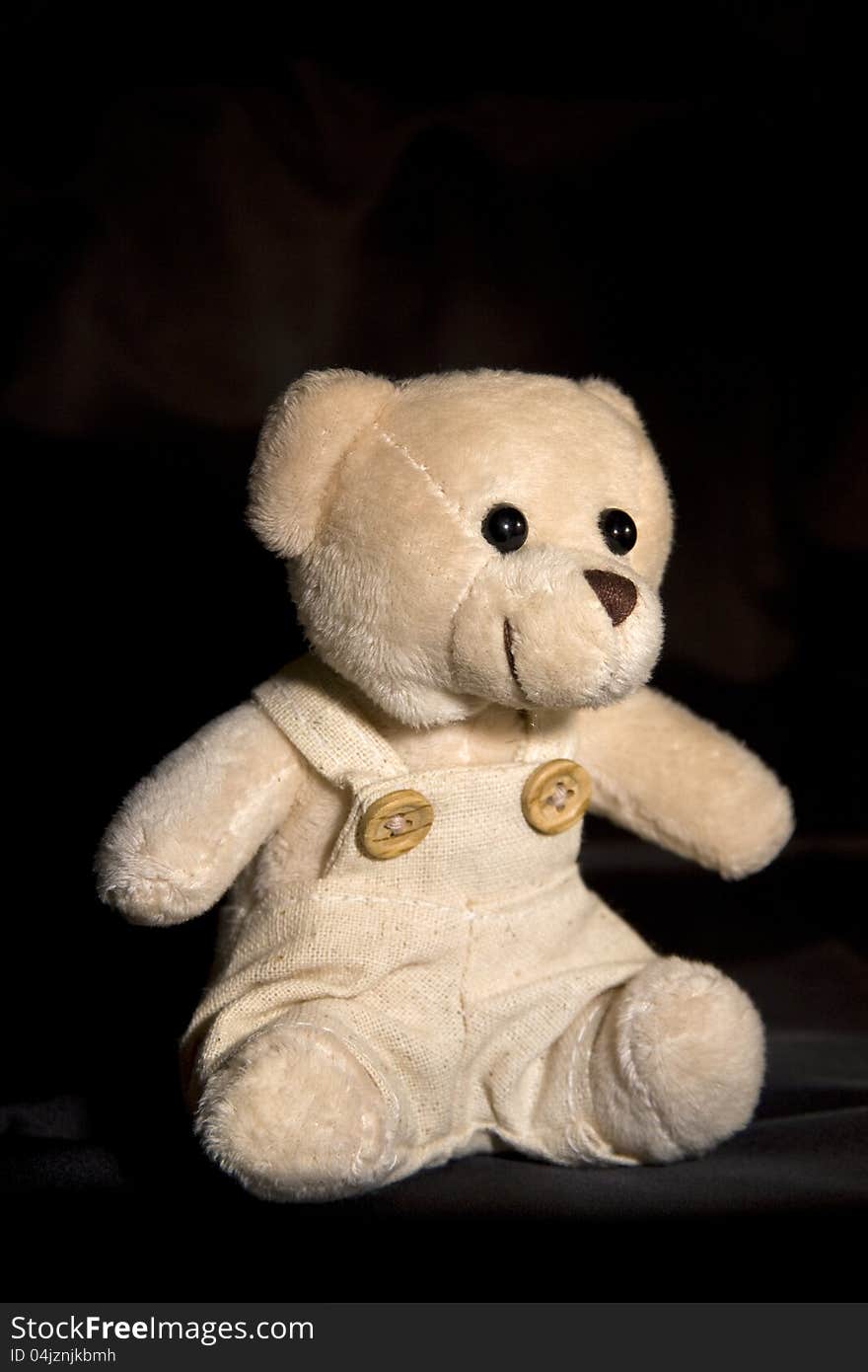 Light brown teddy bear on a black background